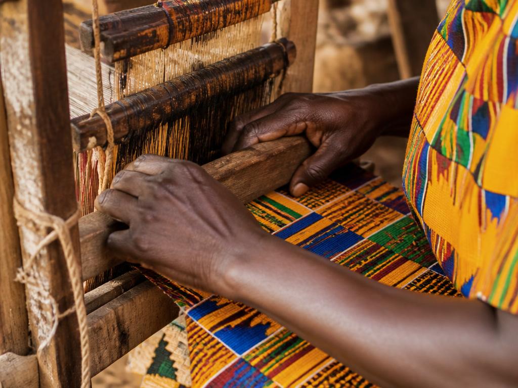 Artisan weaving colorful African textile in sunlight